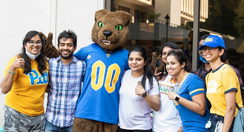 new Pitt grad students posing with Panther mascot Roc during orientation picnic