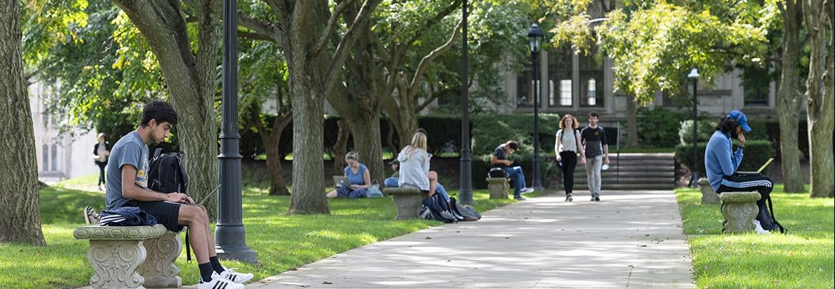 students sit along the Cathedral walkway to study outdoors on a nice day