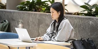 Student studying on laptop with earbuds in